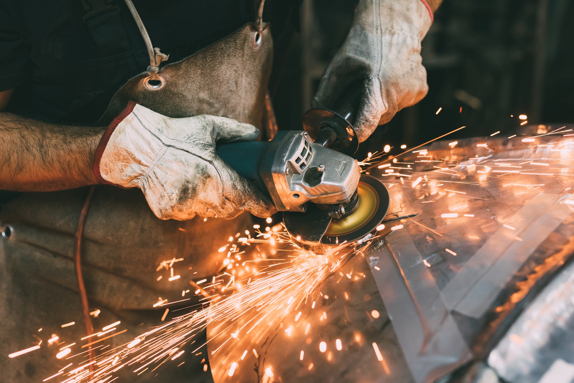 Hands of metalworker grinding copper in forge workshop - functional metalwork