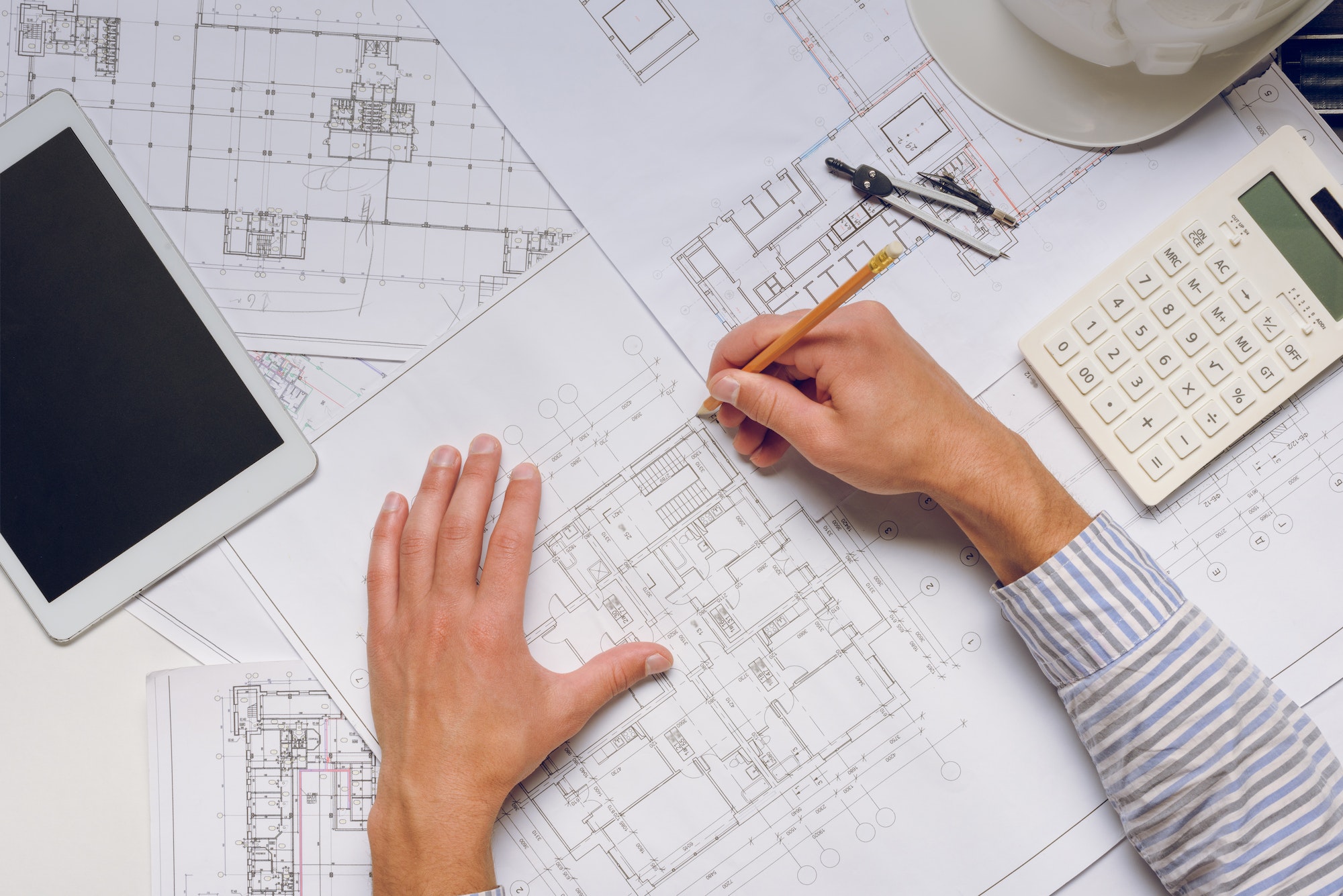 partial view of architect working with blueprints on new building design